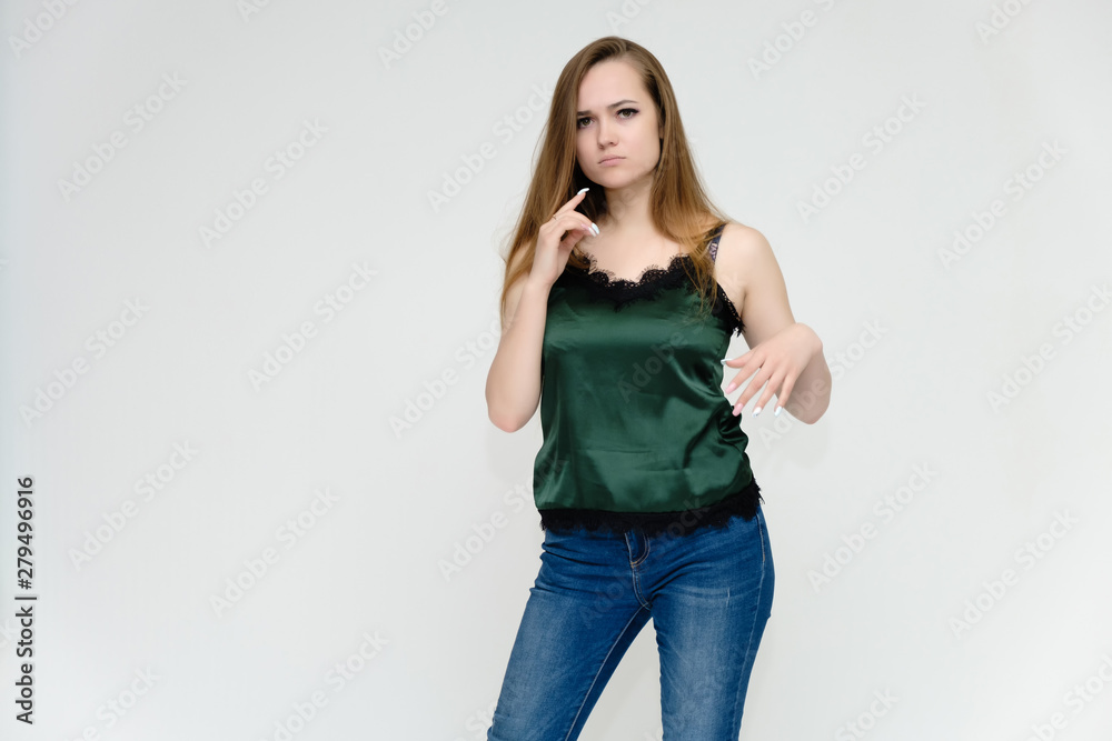 Concept portrait above the knee of a pretty girl, a young woman with long beautiful brown hair and a green t-shirt and blue jeans on a white background. In studio in different poses showing emotions. Concept portrait above the knee of a pretty girl, a young woman with long beautiful brown hair and a green t-shirt and blue jeans on a white background. In studio in different poses showing emotions.