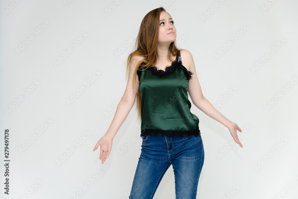 Concept portrait above the knee of a pretty girl, a young woman with long beautiful brown hair and a green t-shirt and blue jeans on a white background. In studio in different poses showing emotions. Concept portrait above the knee of a pretty girl, a young woman with long beautiful brown hair and a green t-shirt and blue jeans on a white background. In studio in different poses showing emotions.