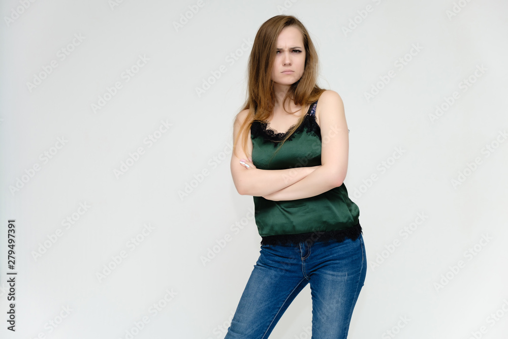 Concept portrait above the knee of a pretty girl, a young woman with long beautiful brown hair and a green t-shirt and blue jeans on a white background. In studio in different poses showing emotions. Concept portrait above the knee of a pretty girl, a young woman with long beautiful brown hair and a green t-shirt and blue jeans on a white background. In studio in different poses showing emotions.