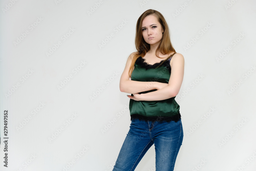 Concept portrait above the knee of a pretty girl, a young woman with long beautiful brown hair and a green t-shirt and blue jeans on a white background. In studio in different poses showing emotions. Concept portrait above the knee of a pretty girl, a young woman with long beautiful brown hair and a green t-shirt and blue jeans on a white background. In studio in different poses showing emotions.