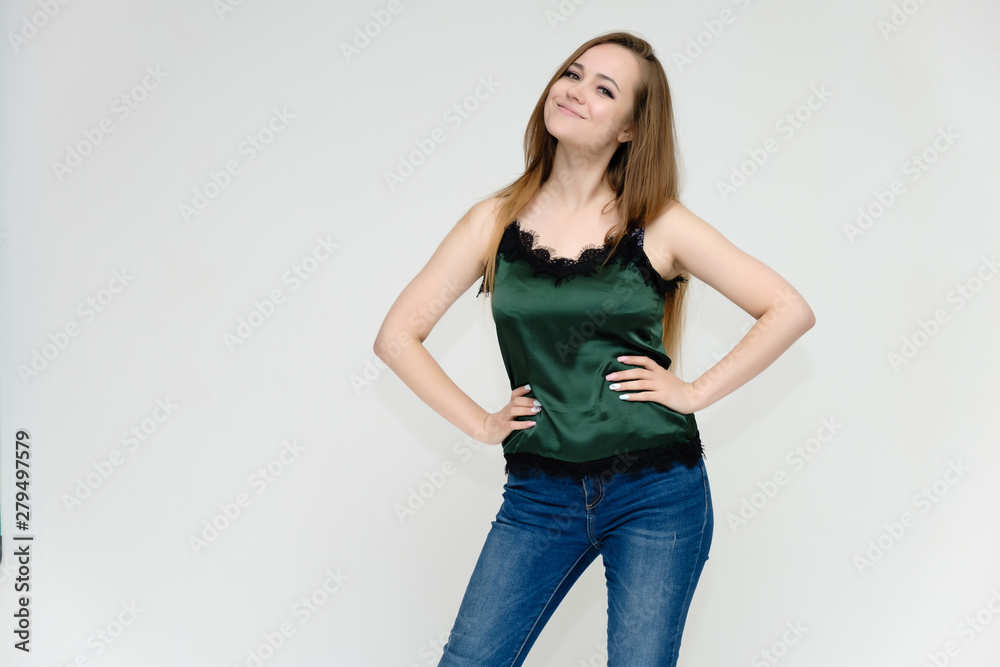 Concept portrait above the knee of a pretty girl, a young woman with long beautiful brown hair and a green t-shirt and blue jeans on a white background. In studio in different poses showing emotions. Concept portrait above the knee of a pretty girl, a young woman with long beautiful brown hair and a green t-shirt and blue jeans on a white background. In studio in different poses showing emotions.