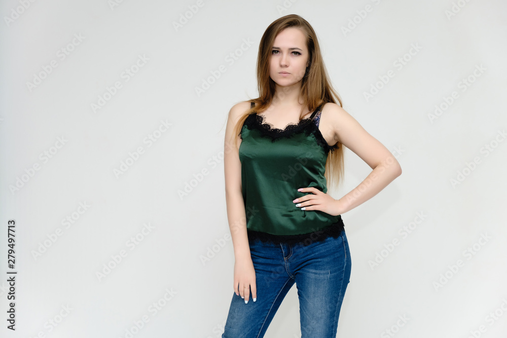 Concept portrait above the knee of a pretty girl, a young woman with long beautiful brown hair and a green t-shirt and blue jeans on a white background. In studio in different poses showing emotions. Concept portrait above the knee of a pretty girl, a young woman with long beautiful brown hair and a green t-shirt and blue jeans on a white background. In studio in different poses showing emotions.