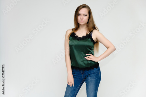 Concept portrait above the knee of a pretty girl, a young woman with long beautiful brown hair and a green t-shirt and blue jeans on a white background. In studio in different poses showing emotions.