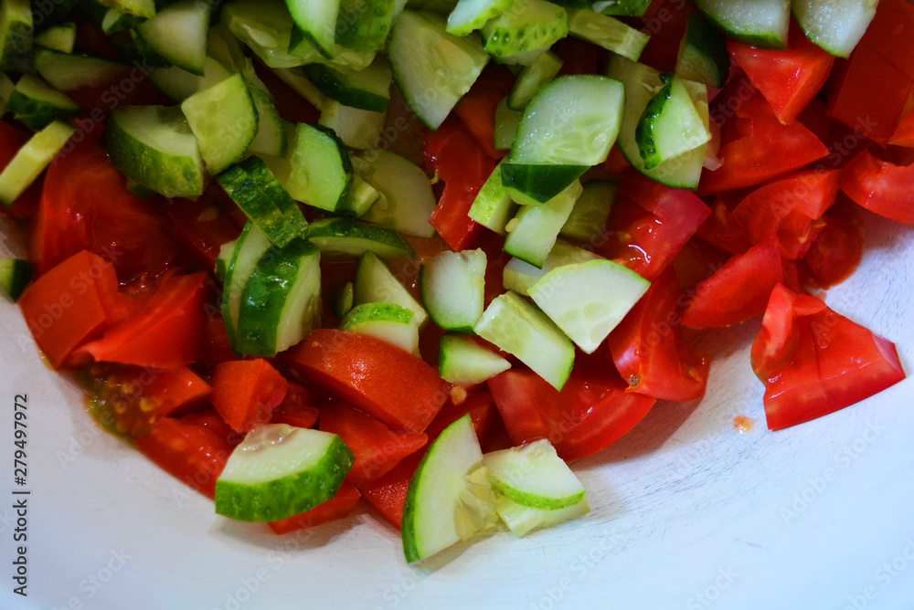 Fresh healthy vegetables, finely chopped green cucumbers and red pomade for summer salad, ingredients for salad.