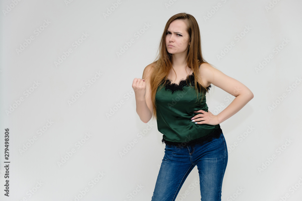 Concept portrait above the knee of a pretty girl, a young woman with long beautiful brown hair and a green t-shirt and blue jeans on a white background. In studio in different poses showing emotions. Concept portrait above the knee of a pretty girl, a young woman with long beautiful brown hair and a green t-shirt and blue jeans on a white background. In studio in different poses showing emotions.