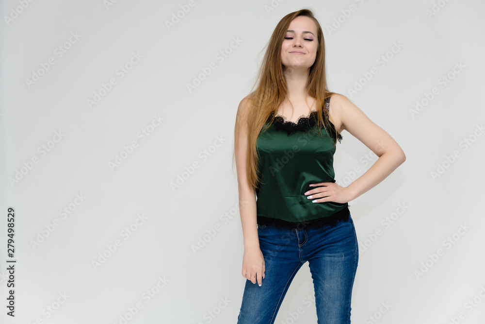 Concept portrait above the knee of a pretty girl, a young woman with long beautiful brown hair and a green t-shirt and blue jeans on a white background. In studio in different poses showing emotions. Concept portrait above the knee of a pretty girl, a young woman with long beautiful brown hair and a green t-shirt and blue jeans on a white background. In studio in different poses showing emotions.