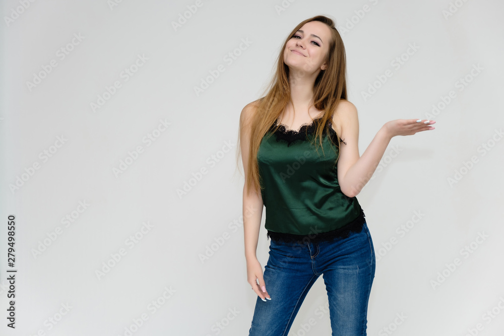 Concept portrait above the knee of a pretty girl, a young woman with long beautiful brown hair and a green t-shirt and blue jeans on a white background. In studio in different poses showing emotions. Concept portrait above the knee of a pretty girl, a young woman with long beautiful brown hair and a green t-shirt and blue jeans on a white background. In studio in different poses showing emotions.