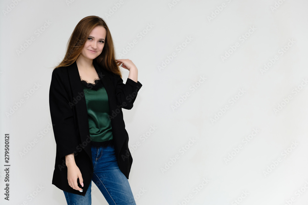 Concept portrait above the knee of a pretty girl, a young woman with long beautiful brown hair and a black jacket and blue jeans on a white background. In studio in different poses showing emotions. Concept portrait above the knee of a pretty girl, a young woman with long beautiful brown hair and a black jacket and blue jeans on a white background. In studio in different poses showing emotions.