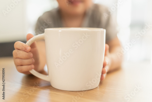 Child holding a cup with foamed milk