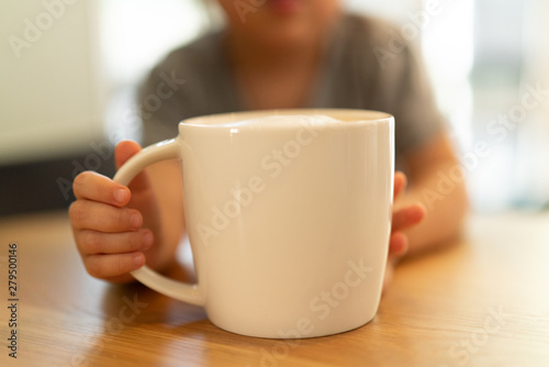 Child holding a cup with foamed milk