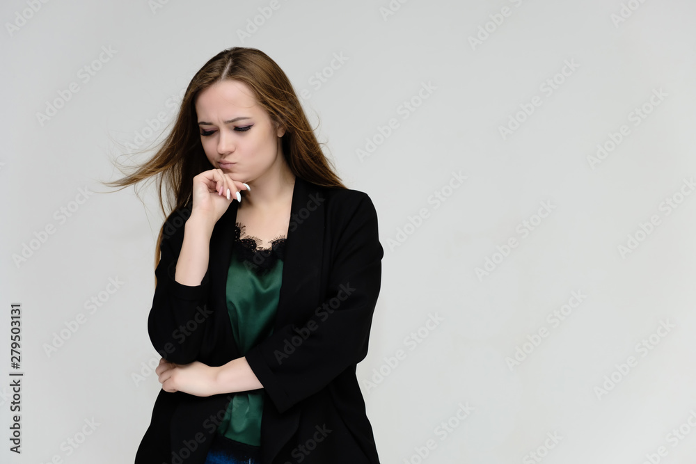 Concept portrait for the waist of a pretty girl, a young woman with long beautiful brown hair and a black jacket and blue jeans on a white background. In studio in different poses showing emotions. Concept portrait for the waist of a pretty girl, a young woman with long beautiful brown hair and a black jacket and blue jeans on a white background. In studio in different poses showing emotions.
