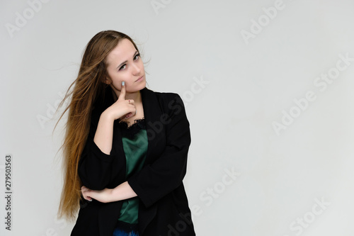 Concept portrait for the waist of a pretty girl, a young woman with long beautiful brown hair and a black jacket and blue jeans on a white background. In studio in different poses showing emotions.