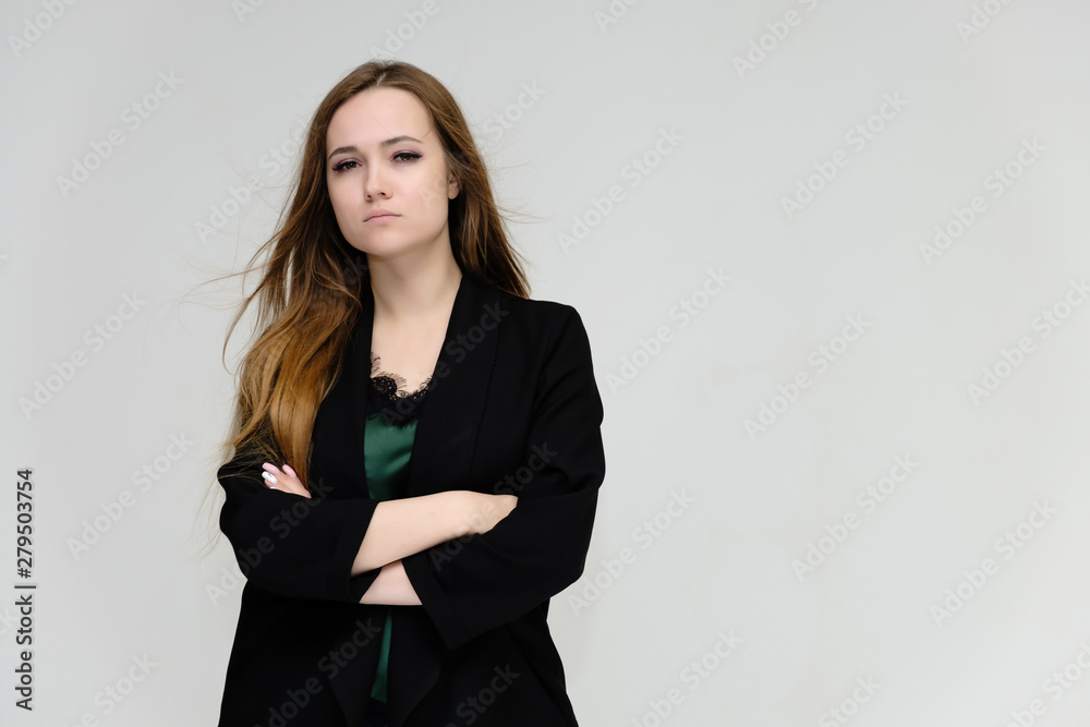 Concept portrait for the waist of a pretty girl, a young woman with long beautiful brown hair and a black jacket and blue jeans on a white background. In studio in different poses showing emotions. Concept portrait for the waist of a pretty girl, a young woman with long beautiful brown hair and a black jacket and blue jeans on a white background. In studio in different poses showing emotions.