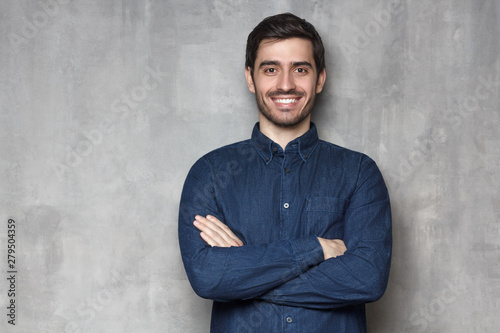 Positive European guy leaning on wall, smiling, isolted on background