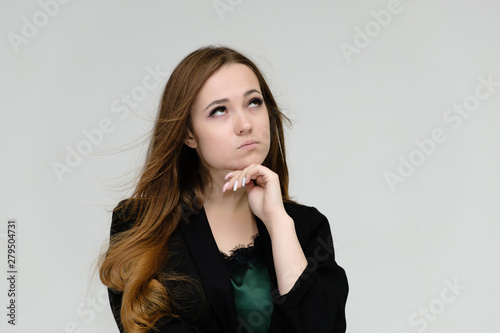 Concept close-up portrait of a pretty girl, a young woman with long beautiful brown hair and a black jacket on a white background. In the studio in different poses showing emotions.
