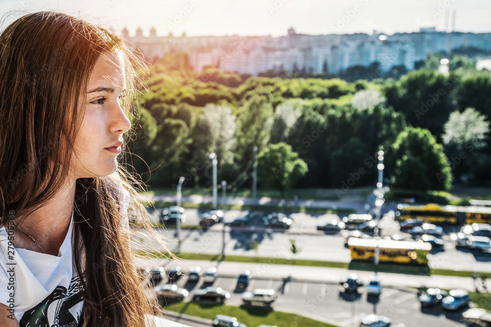 profile portrait of young girl with long hair, cityscape background