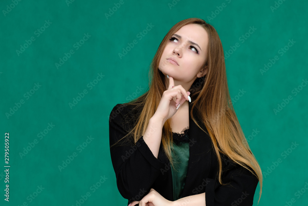 Concept close-up portrait of a pretty girl, a young woman with long beautiful brown hair and in a black jacket on a green background. In the studio in different poses showing emotions. Concept close-up portrait of a pretty girl, a young woman with long beautiful brown hair and in a black jacket on a green background. In the studio in different poses showing emotions.