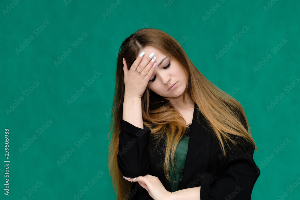 Concept close-up portrait of a pretty girl, a young woman with long beautiful brown hair and in a black jacket on a green background. In the studio in different poses showing emotions.