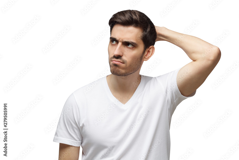 Young doubtful man scratching his head trying to find solution, isolated on gray background Young doubtful man scratching his head trying to find solution, isolated on gray background