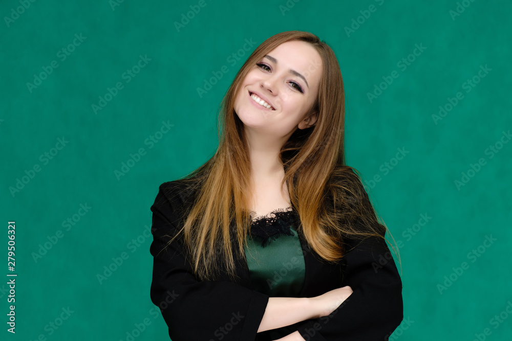 Concept close-up portrait of a pretty girl, a young woman with long beautiful brown hair and in a black jacket on a green background. In the studio in different poses showing emotions.