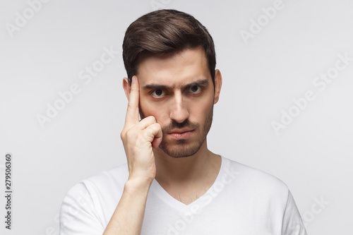 Close-up portrait of suspicious man thinking, trying to read your thoughts, isolated on gray background
