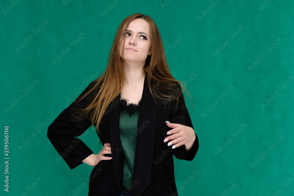 Concept portrait for a belt of a pretty girl, young woman with beautiful brown hair and in a black jacket and green T-shirt on a green background. In the studio in different poses showing emotions. Concept portrait for a belt of a pretty girl, young woman with beautiful brown hair and in a black jacket and green T-shirt on a green background. In the studio in different poses showing emotions.