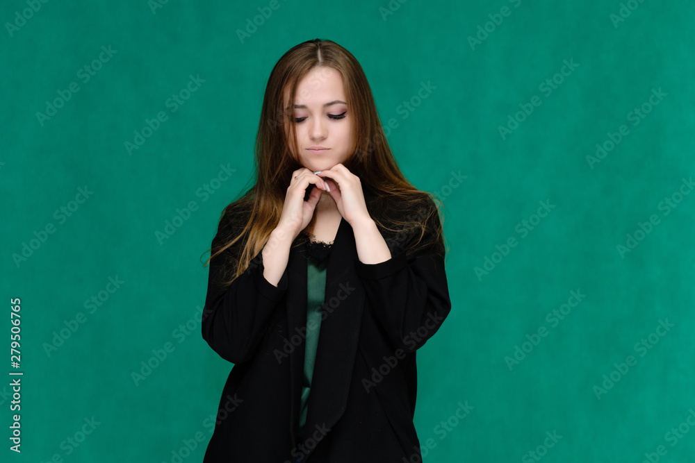 Concept portrait for a belt of a pretty girl, young woman with beautiful brown hair and in a black jacket and green T-shirt on a green background. In the studio in different poses showing emotions. Concept portrait for a belt of a pretty girl, young woman with beautiful brown hair and in a black jacket and green T-shirt on a green background. In the studio in different poses showing emotions.