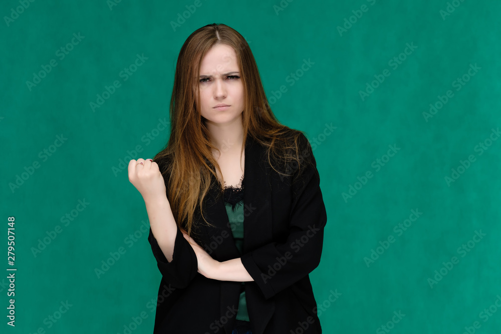 Concept portrait for a belt of a pretty girl, young woman with beautiful brown hair and in a black jacket and green T-shirt on a green background. In the studio in different poses showing emotions. Concept portrait for a belt of a pretty girl, young woman with beautiful brown hair and in a black jacket and green T-shirt on a green background. In the studio in different poses showing emotions.