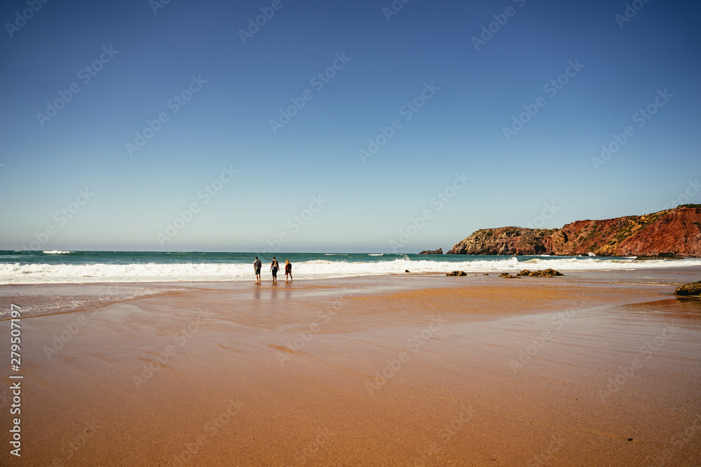 Surfers entering the ocean at Praia do Amado