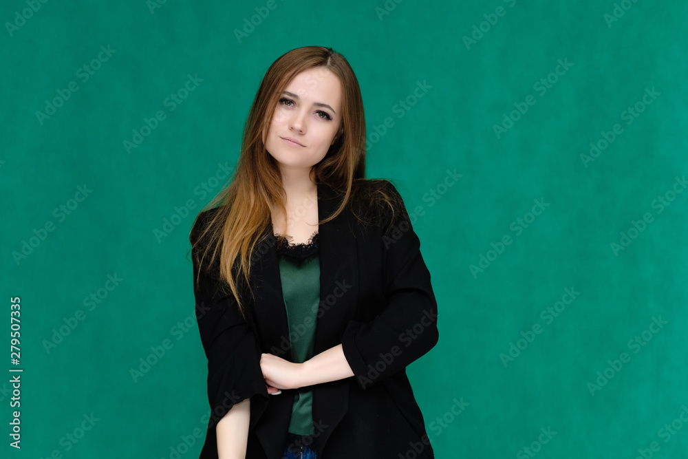 Concept portrait for a belt of a pretty girl, young woman with beautiful brown hair and in a black jacket and green T-shirt on a green background. In the studio in different poses showing emotions. Concept portrait for a belt of a pretty girl, young woman with beautiful brown hair and in a black jacket and green T-shirt on a green background. In the studio in different poses showing emotions.