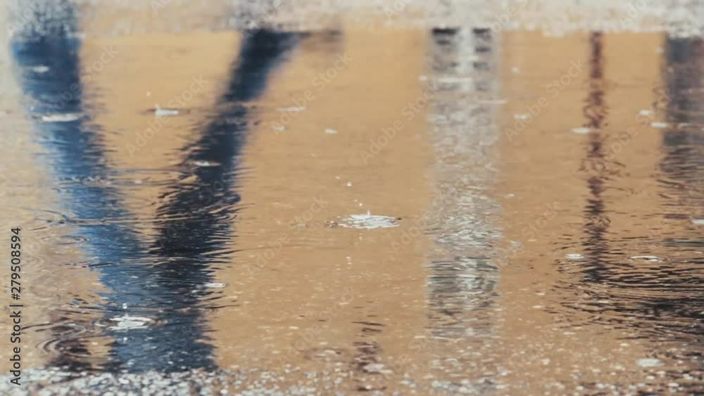 Rainy day. Someone wearing blue jeans passing through and mirroring in reflection in puddle on asphalt. Slow motion. Rainy day. Someone wearing blue jeans passing through and mirroring in reflection in puddle on asphalt. Slow motion.