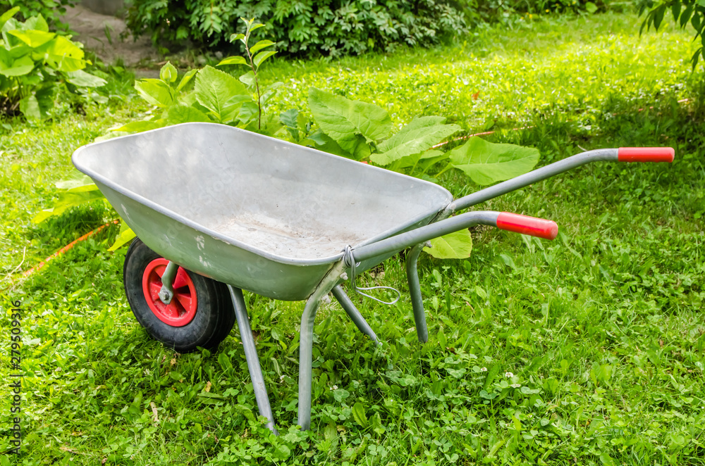 garden trolley with red handles and wheels stands on the grass garden trolley with red handles and wheels stands on the grass