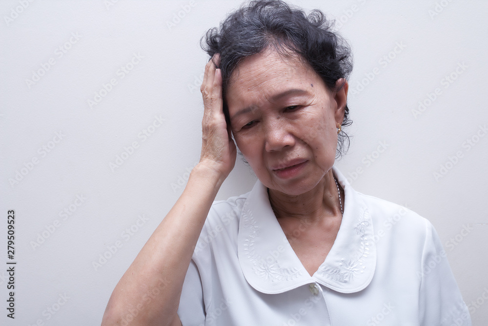 Elderly Asian woman holding her head, having a strong headache and fever Elderly Asian woman holding her head, having a strong headache and fever