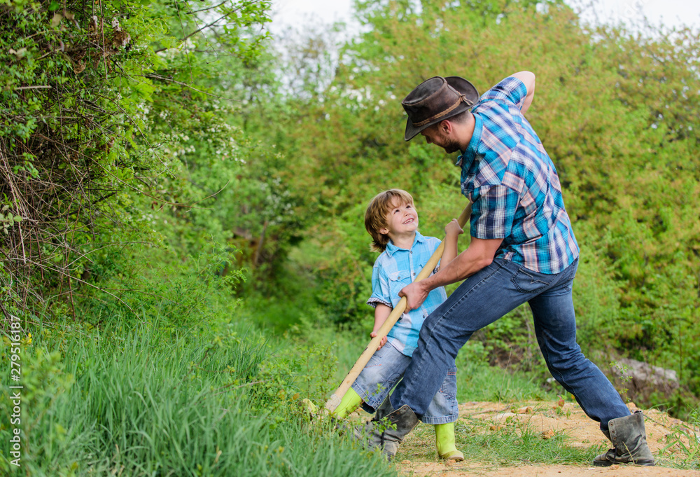 Happy childhood. Adventure hunting for treasures. Little helper in garden. Cute child in nature having fun with cowboy dad. Find treasures. Little boy and father with shovel looking for treasures