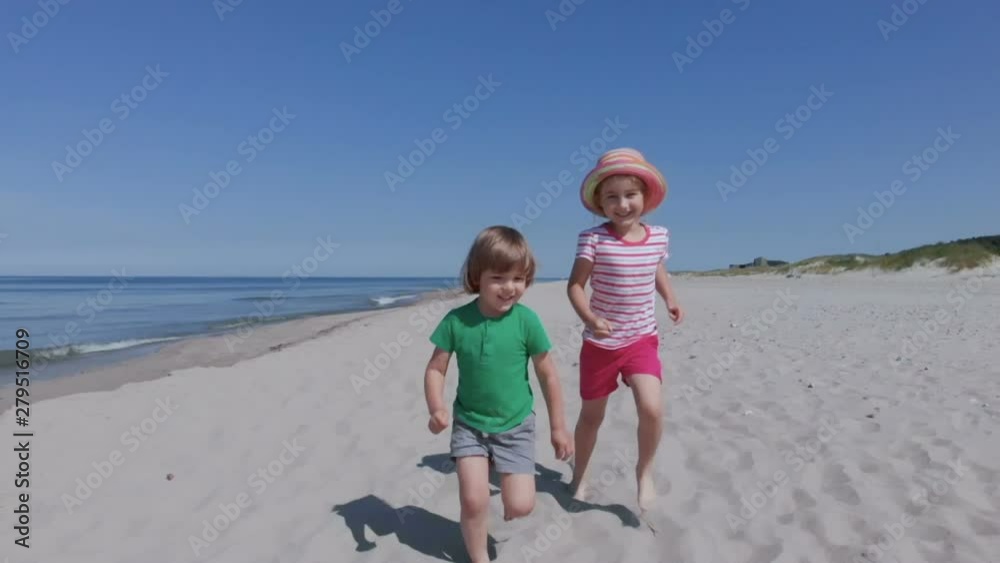 Aerial. Portrait of children on beach in summer. Happy children, boy girl, brother and sister running and having fun playing in sand on a beach. Slow motion. Happy children playing on beach. Aerial. Portrait of children on beach in summer. Happy children, boy girl, brother and sister running and having fun playing in sand on a beach. Slow motion. Happy children playing on beach.