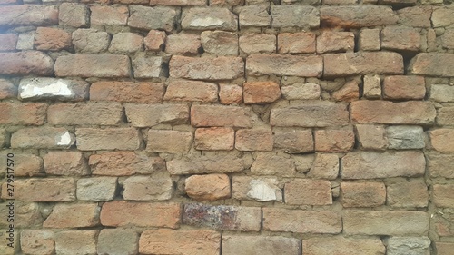 A background of a weathered old exterior brick wall in the sunshine.