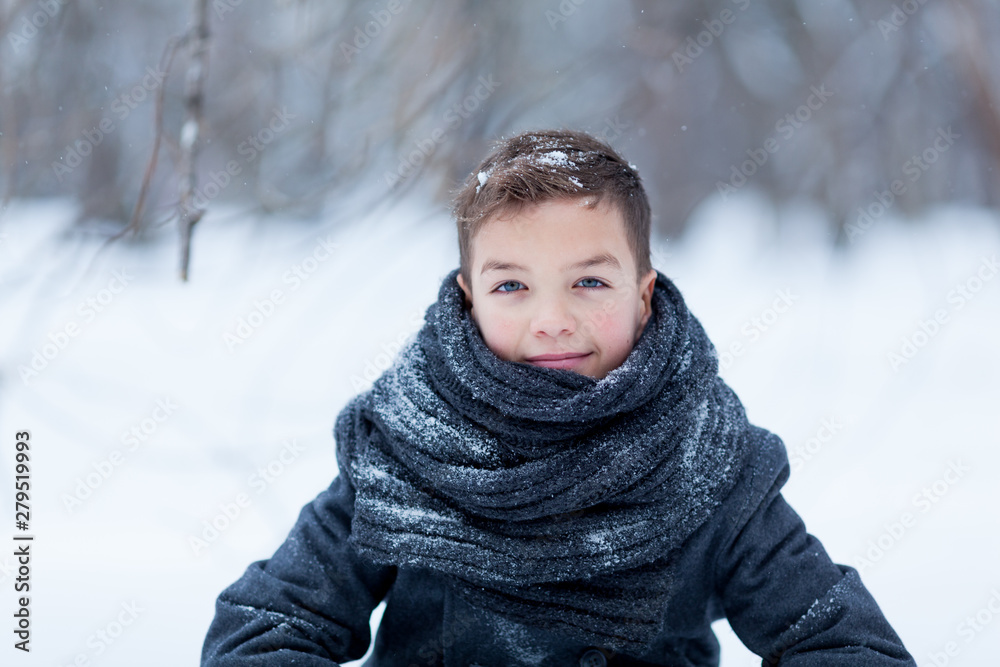 Portrait of happy boy in black coat for walk in winter park, outdoor