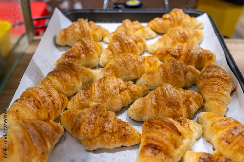 Fresh baked butter croissants on tray in pastry shop
