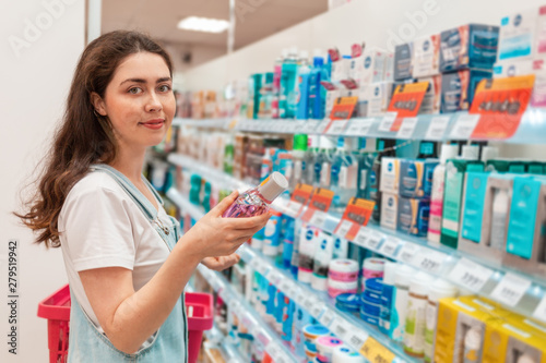 Free Download A young beautiful woman smiles and chooses a mouthwash. Purchase and sale of goods in the store - GFXLoad