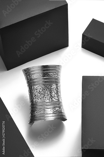 фотографія Close-up shot of a cuff bracelet with vintage ornament which looks like Egyptian or Greek armlet made of patterned silver metal