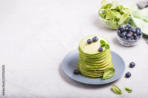 Stack of green spinach pancakes, healthy breakfast or snack, vegetarian food on copy space concrete background