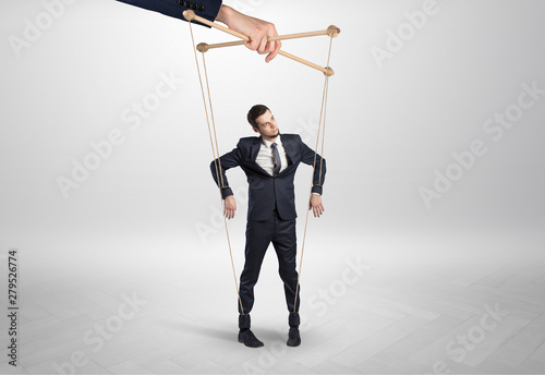 Puppet businessman in an empty room leaded by a huge hand