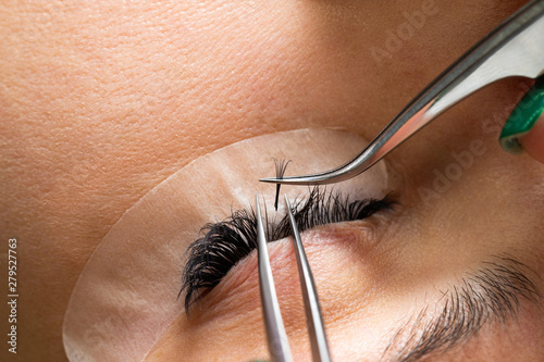 The master builds up large colored eyelashes to the client. Preparation for beauty photography. Creating an image.