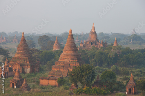 Orange mystical sunrise landscape view with silhouettes of old ancient temples and palm trees in dawn fog from balloon  Bagan  Myanmar. Burma
