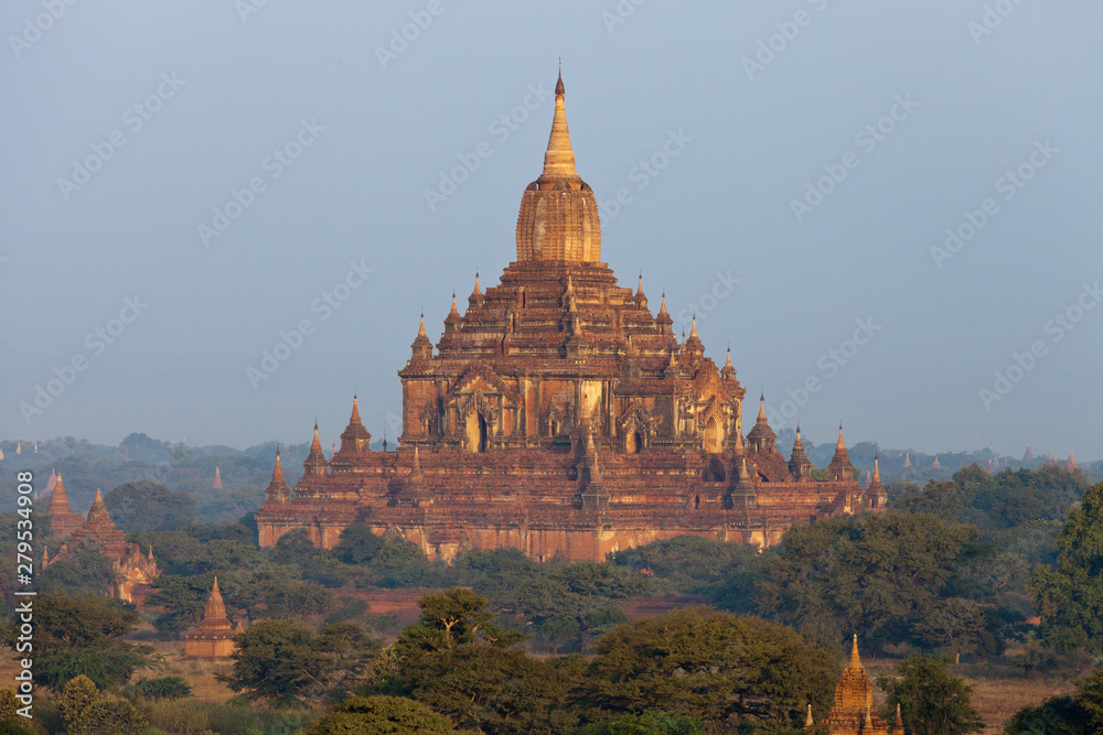 Orange mystical sunrise landscape view with silhouettes of old ancient temples and palm trees in dawn fog from balloon, Bagan, Myanmar. Burma