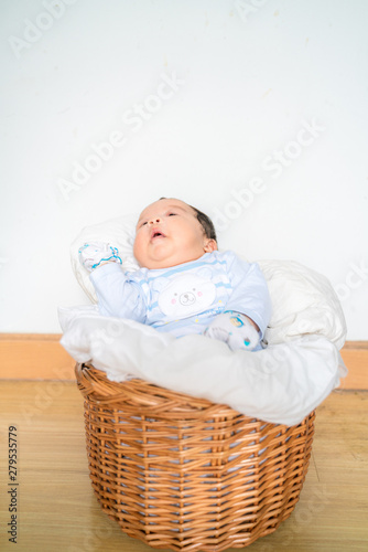 Adorable infant baby lying in wood basket with blanket