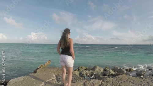 mujer caminando por la playa viendo el horizonte 