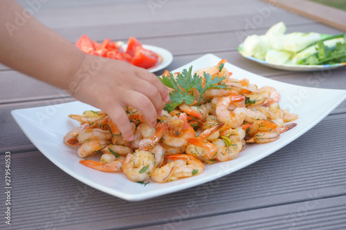 shrimps, children's hands take shrimps from the plate