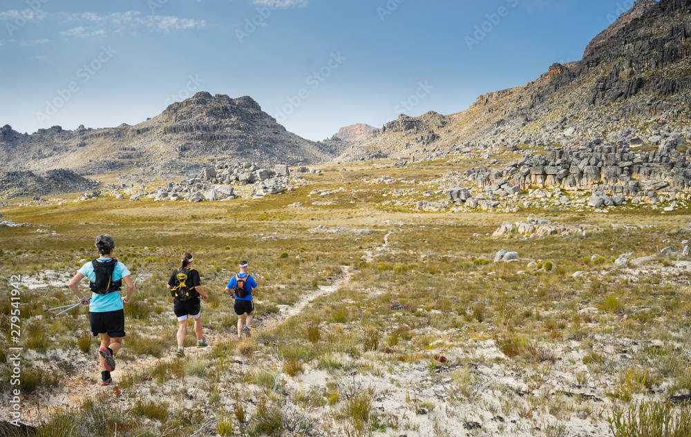 A group of trail runners running along a mountain trail