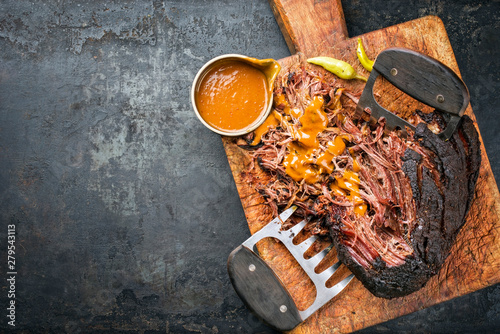 Traditional barbecue wagyu pulled beef with spicy sauce as top view on a rustic cutting board with copy space left photo